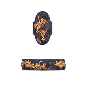 Kyo Kinko Dragon Fuchi Kashira The fuchi depicts a dragon emerging dynamically from stylized waves, while the kashira presents a counterpart dragon soaring through clouds. Notably, the dragon on the fuchi bears the sacred jewel (hoju) just behind its head—an iconographic detail often seen in the Goto school, though this work is attributed to the Kyoto Kinko tradition. While clearly influenced by the Goto style, it is not a Goto piece itself, but rather the work of a Kyoto-based workshop that emulated Goto aesthetics. The dragons are masterfully carved with rich detail and expressive relief. Their pupils are inlaid in shakudo, adding lifelike intensity to their gaze. An additional rare feature is the shitodome, or cord inserts, on the kashira: they are also made of shakudo, which is uncommon, as copper is usually used. The piece dates to the early to mid Edo period, and exemplifies the high level of craftsmanship and stylistic refinement characteristic of Kyoto Kinko artists who operated in the stylistic orbit of the prestigious Goto lineage.